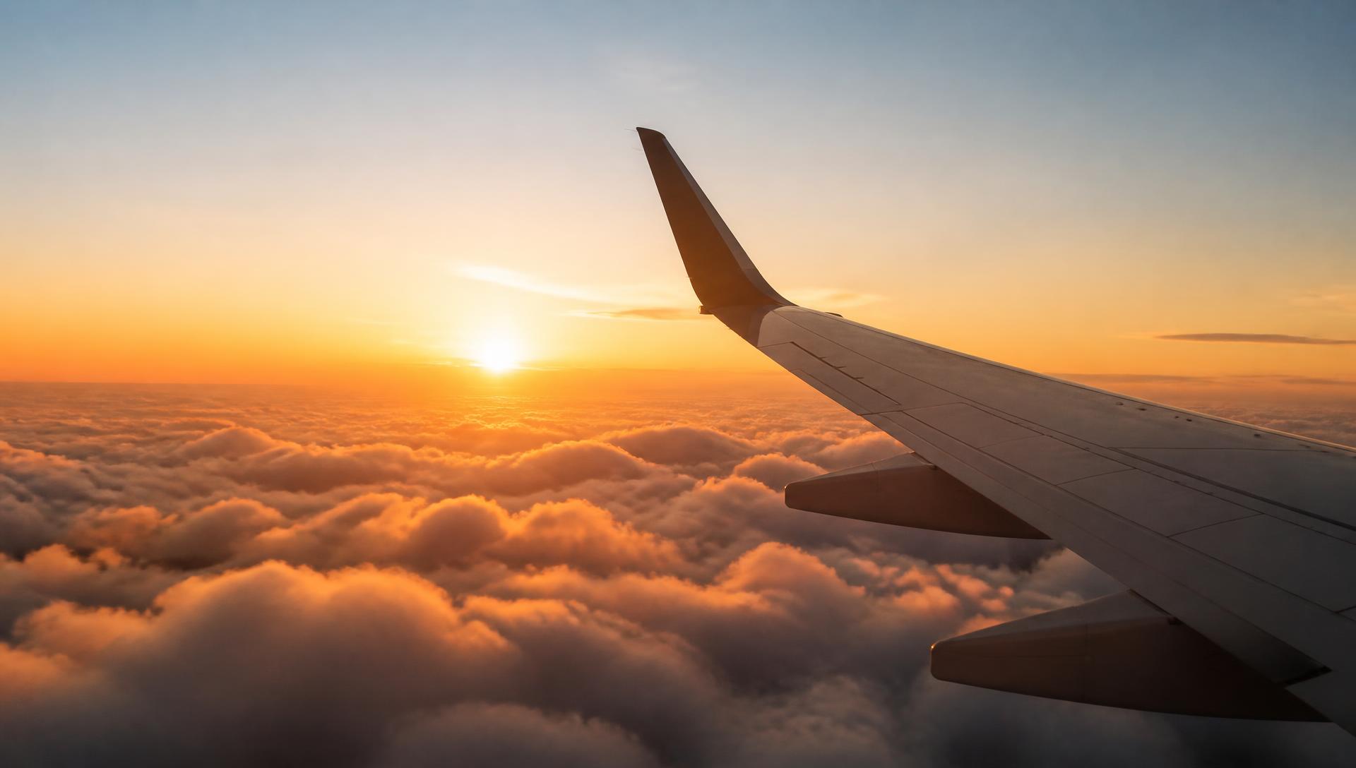Asa de avião sobre um mar de nuvens douradas ao pôr do sol